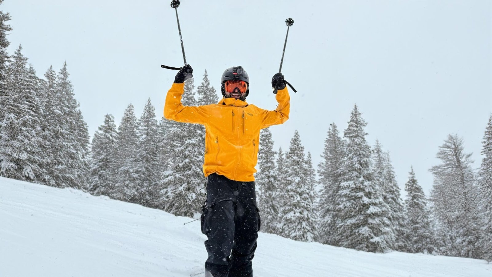 Cameron skiing in the mountains, hands up in success