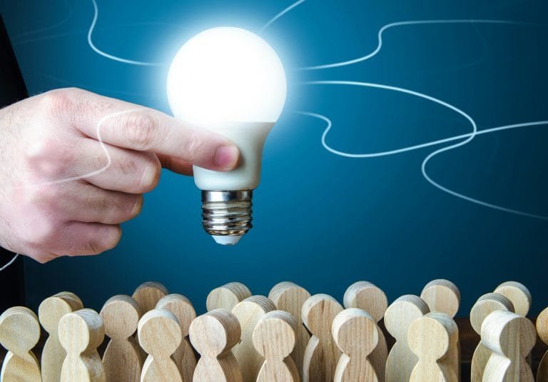 A man holds an idea light bulb above the crowd.